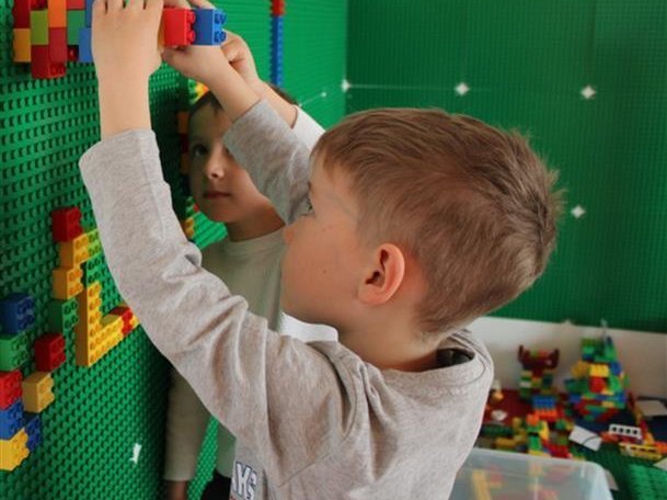 Foto aus dem Kindergarten: Junge spielt Lego an einer Legowand