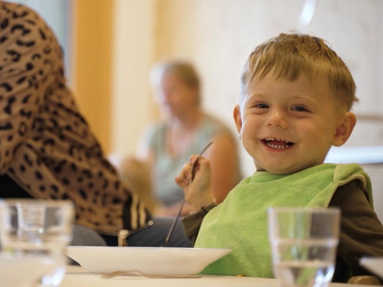 Lachender Junge beim Essen.