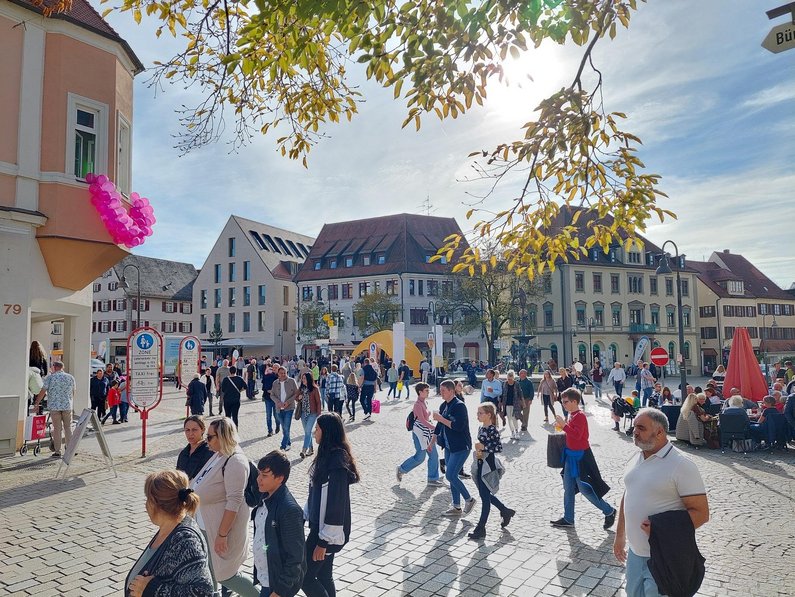 Viele Menschen laufen bei Sonnenschein über den Marktplatz
